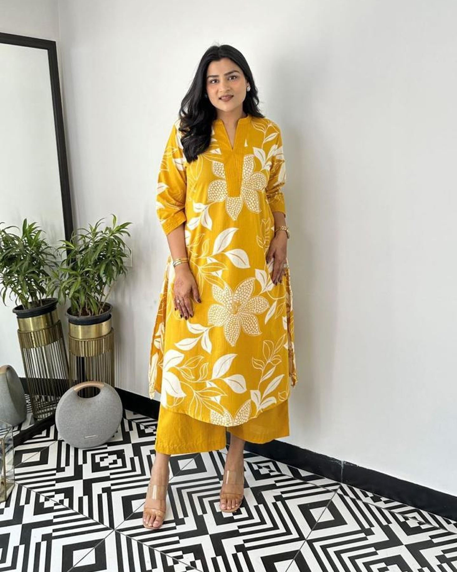 Woman in a yellow floral dress standing in a room with a geometric floor pattern.
